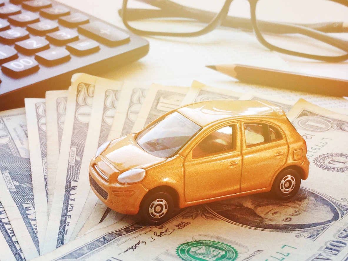 Business, finance, saving money, banking or car loan concept : Miniature car model, calculator, dollar money and saving account book or financial statement on office desk table