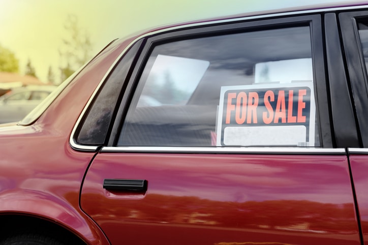 shiny car for sale in summer weather, parked with a red vibrant color exterior.